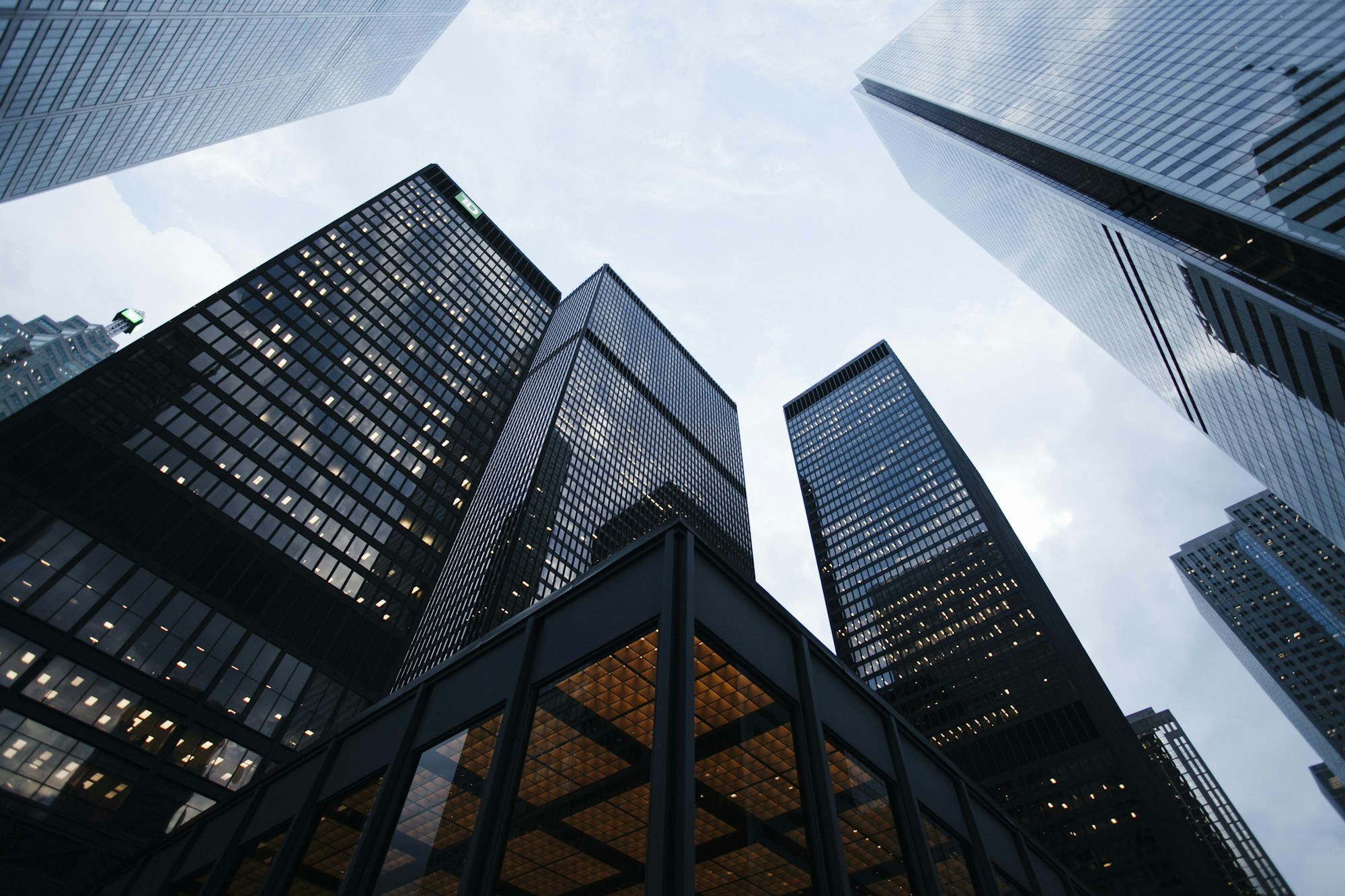 An upward view between sculptural concrete and glass towers